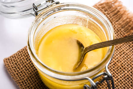 Desi Pure Ghee or clarified butter in glass or Copper container with spoon, selective focus