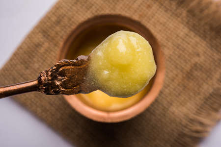 Desi Pure Ghee or clarified butter in glass or Copper container with spoon, selective focus