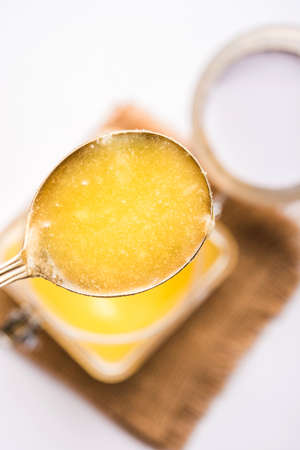 Desi Pure Ghee or clarified butter in glass or Copper container with spoon, selective focus