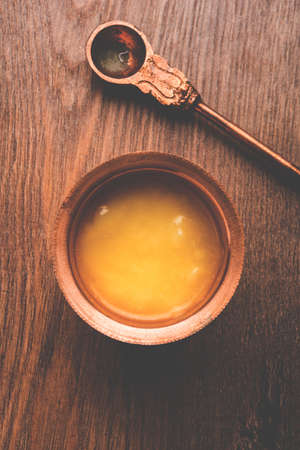 Desi Pure Ghee or clarified butter in glass or Copper container with spoon, selective focus