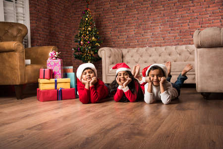 Indian kids celebrating christmas with christmas gifts, decorating christmas tree and having good timeの写真素材