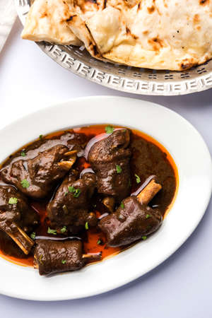 lamb shank or mutton or gosht paya or khoor curry served with indian bread or roti or naan