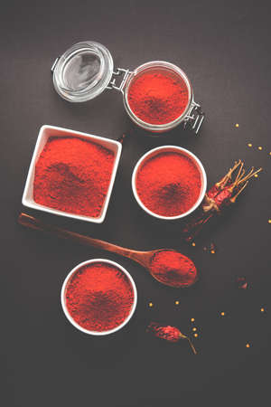 Red Chilly Powder in a bowl with dried red chillies over colourful background or pile of red chilli...