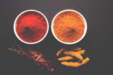 heap of turmeric and red chilli powder in a ceramic bowl on a white or black backgroundの写真素材