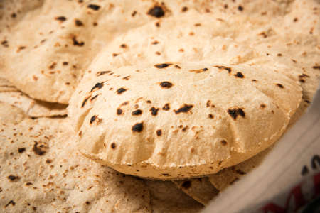 Roti or chapati making machine, selective focus. Indian ready to eat Indian flat bread coming out of...