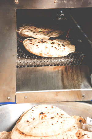 Roti or chapati making machine, selective focus. Indian ready to eat Indian flat bread coming out of machineの写真素材