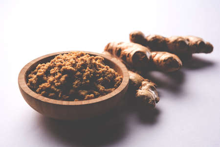Fresh mashed Ginger / Ginger paste in white bowl with raw ginger over white background