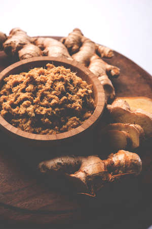 Fresh mashed Ginger / Ginger paste in white bowl with raw ginger over white backgroundの写真素材
