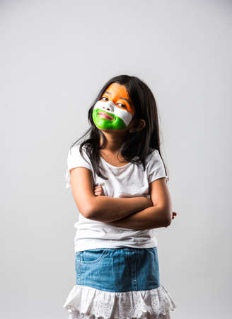 indian girl with paper windmill toy made up of tricolour or indian flag colours. Saluting, looking at camera or with red heart toy, celebrating 26 January republic day or 15 august independence dayの写真素材