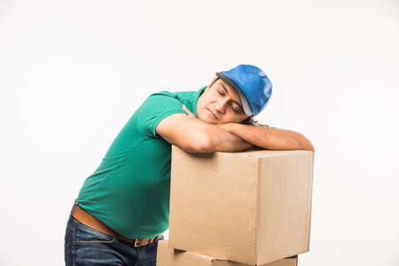 Delivery Concept - Portrait of Happy Indian or delivery man in red or green uniform walking or jumping or checking or presenting cardboard box with copy spaceの写真素材