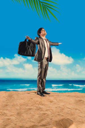 Indian businessman relaxing on beach with cold drinks or laptop, beach ball, talking on phone or with hands spreadの写真素材