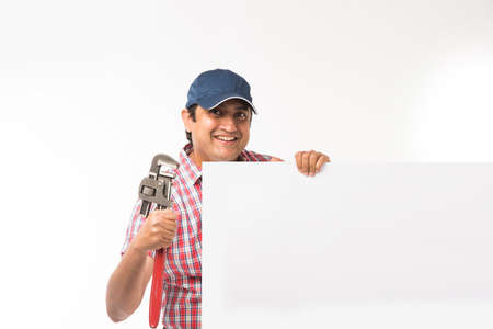 Indian plumber posing with Pipe wrench or plumbing spanner, standing isolated over white background