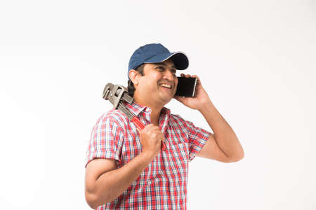 Indian plumber posing with Pipe wrench or plumbing spanner, standing isolated over white backgroundの写真素材