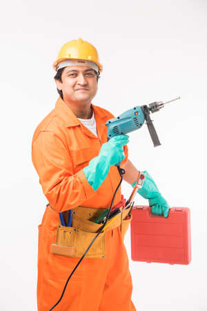 Indian electrician engineer in action with wire cutter, drilling machine etc, standing isolated over...