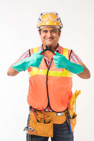 Indian electrician engineer in action with wire cutter, drilling machine etc, standing isolated over white backgroundの写真素材