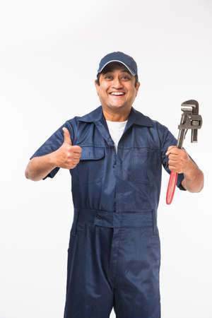 Indian plumber posing with Pipe wrench or plumbing spanner, standing isolated over white backgroundの写真素材