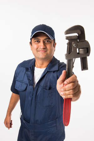 Indian plumber posing with Pipe wrench or plumbing spanner, standing isolated over white backgroundの写真素材