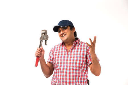 Indian plumber posing with Pipe wrench or plumbing spanner, standing isolated over white backgroundの写真素材