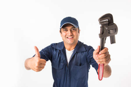 Indian plumber posing with Pipe wrench or plumbing spanner, standing isolated over white backgroundの写真素材