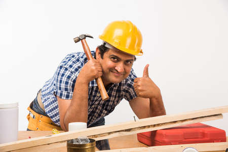 Handsome Indian Carpenter or wood worker in action, isolated over white background