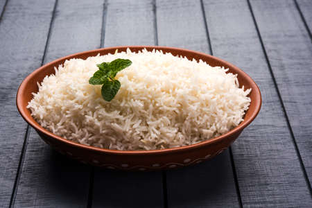 Cooked plain white basmati rice in terracotta bowl over plain or wooden backgroundの写真素材