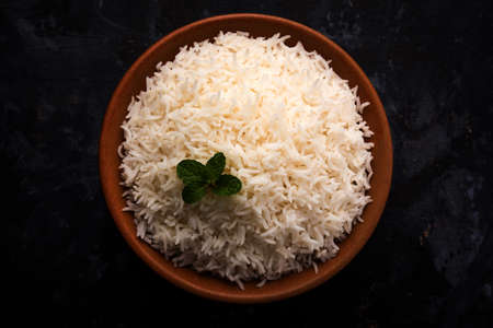 Cooked plain white basmati rice in terracotta bowl over plain or wooden backgroundの写真素材