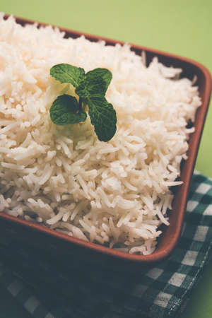 Cooked plain white basmati rice in terracotta bowl over plain or wooden backgroundの写真素材