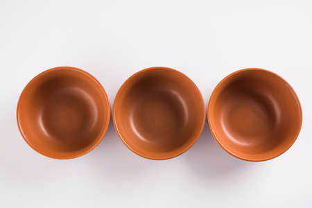 Empty terracotta serving bowl or brown clay soup bowl isolated on whiteの写真素材