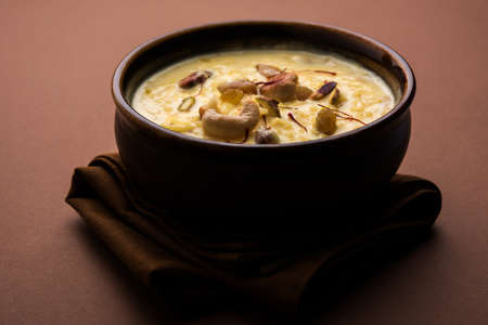 kheer or rice pudding is an Indian dessert in a brown terracotta bowl with dry fruits toppingsの写真素材