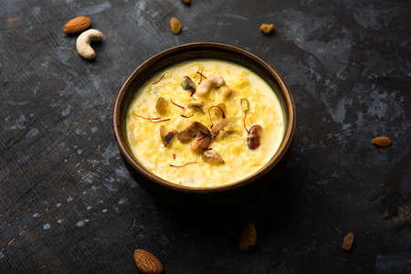 kheer or rice pudding is an Indian dessert in a brown terracotta bowl with dry fruits toppings