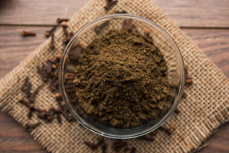 whole Cloves or laung or lavang with powder in a bowl isolated on white. Whole cloves. Selective...