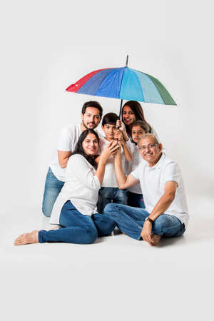 Indian Family sitting with Umbrella over white background. selective focusの写真素材
