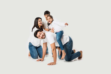 happy mad ride on father's back. Indian small girl sitting on Dad's back while mother and brother...