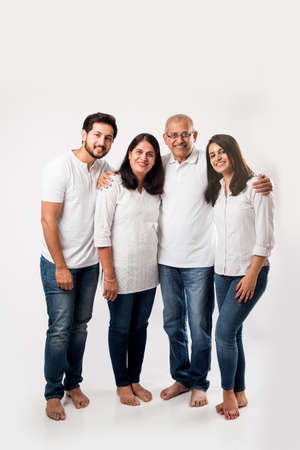 happy Indian family standing isolated over white background. senior parents with young kids wearing...