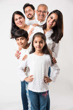 Indian family standing isolated over white background. senior and  young couple with kids wearing...