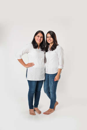 Indian old mother with young Daughter standing isolated over white background, while wearing white...