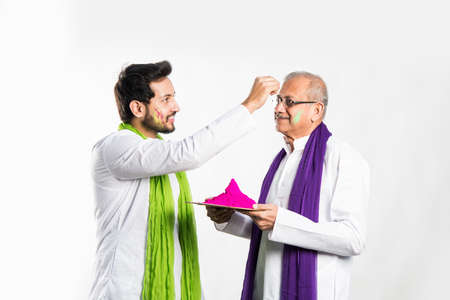 Indian father-son celebrating holi with colours. isolated over white background