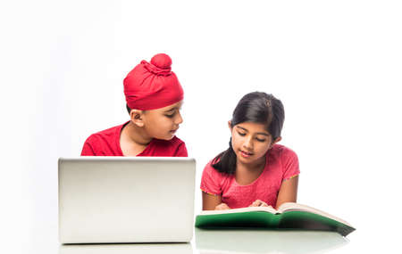 Indian sikh/Punjabi  boy and girl studying with books and laptop computer at study tableの写真素材