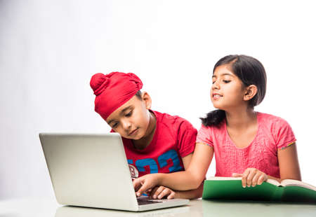 Indian sikh/Punjabi  boy and girl studying with books and laptop computer at study tableの写真素材