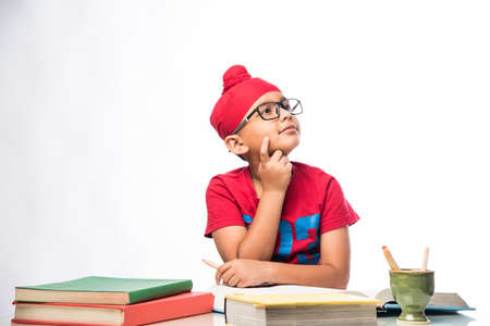 Small Indian/sikh boy studying at study table with books