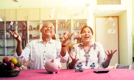 Happy Senior Indian/asian couple having won lottery or investment earning in form of Money/paper...