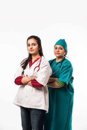 Two women doctors/surgeons standing and looking at the camera in front of medical team and patient - Imageの写真素材