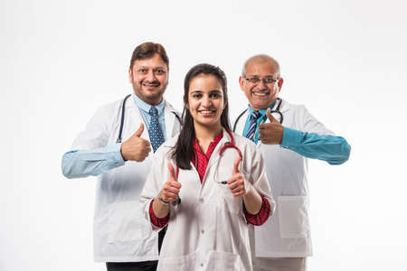 Group of successful Indian medical doctors, male and female standing isolated with thumbs up sign on white background, selective focusの写真素材