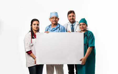 4 indian/asian doctors holding white blank board with copy space, standing isolated over white...
