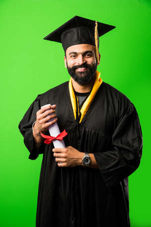 education, graduation and people concept - happy Indian Male graduate student in mortarboard and bachelor gownの写真素材