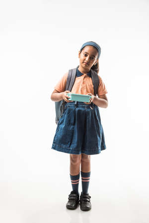 Indian girl in school uniform, standing isolated over white background ready to leave