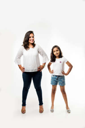 Indian small girl and mother standing over white background measuring height differenceの写真素材