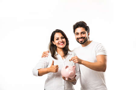 Indian couple with piggy bank standing isolated over white backgroundの写真素材