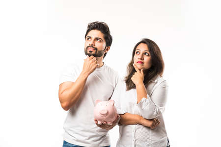 Indian couple with piggy bank standing isolated over white backgroundの写真素材