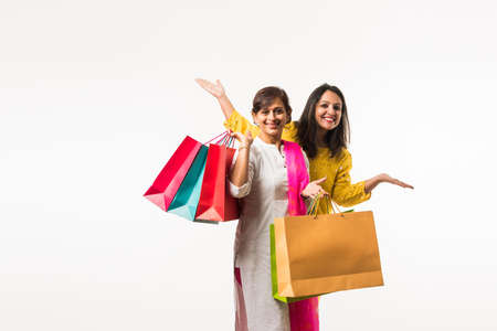 Indian Mother daughter sisters shopping with colourful bags, standing isolated over white backgroundの写真素材